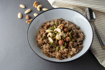 Healthy breakfast bowl. Oatmeal with nuts - walnuts, chia seeds, pumpkin seeds and honey, isolated.