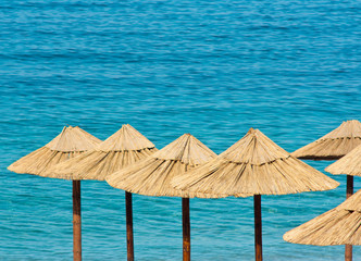 Straw umbrellas on a  beach with turquoise water