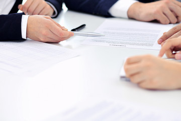 Group of business people and lawyers discussing contract papers sitting at the table, close-up. Successful teamwork, cooperation and agreement concepts