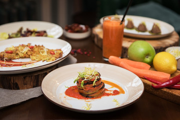 Healthy vegeterian food on brown wood board. Spring vitamin dieting food. Baked vegetables in layers, fruits and carrot juice