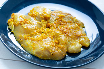 Raw, flavored with turmeric, basil and oregano chicken fillet on a plate.