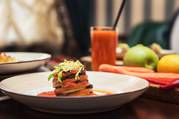 Healthy vegeterian food on brown wood board. Spring vitamin dieting food. Baked vegetables in layers, fruits and carrot juice