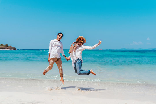 Young happy muslim couple white dress on seashore. Travel Vacation Retirement Lifestyle Concept. young couple jumping on the beach in vacation day. summer time.