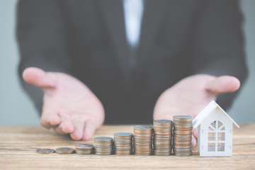 Money of coin stack step up growing growth with model white house on wooden table. Property...