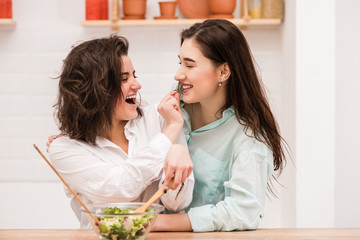Obraz na płótnie Canvas Happy same sex couple feed each other at kitchen