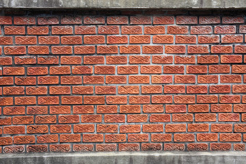 The cement wall is decorated with full orange brick blocks.