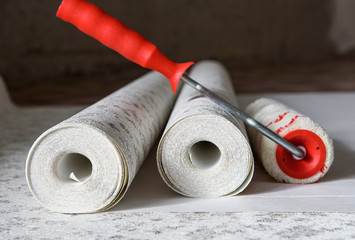 Rolls of wallpaper and roller. Preparation for repair in the apartment.