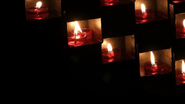 Beautiful red church candles for prayers in special niches in a catholic temple on a black background