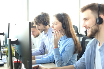 Portrait of call center worker accompanied by her team. Smiling customer support operator at work.