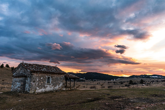 Dramatic colorful sunset in Rhodope mountain, near Dobrostan village. Small chapel "seint Ilia" in front. Bulgaria