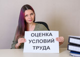 Office employee with a sign "Assessment of working conditions" at the table