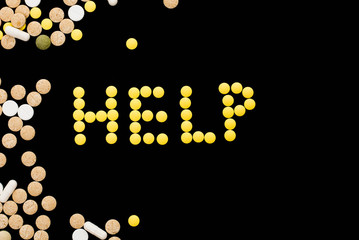 Assorted pharmaceutical medicine pills, tablets and capsules on black background. word help. Help word concept. Creative idea. Drugs. Sad. Die. Illness.