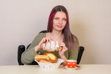 A young girl at the table gets a roll from a plate with pastries