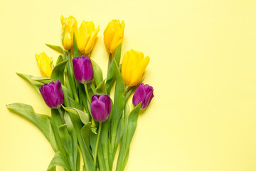 Yellow and purple flowers tulips in a bouquet on a yellow background, a festive spring background greeting card