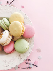 Delicious pink and green macaroons on pink paper, flat lay. Colorful macarons with confetti, candy bar for wedding on birthday. Stylish food Phone photo