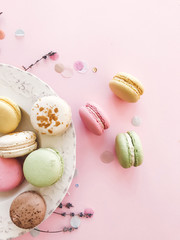Delicious pink and green macaroons on pink paper, flat lay. Colorful macarons with confetti, candy bar for wedding on birthday. Stylish food Phone photo