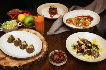 Healthy vegeterian food on brown wood board. Spring vitamin dieting food. Salad from beet with dried tomatoes and cabbage, potato vegan pancakes, dried tomatoes, pate from red beans, baked vegetables