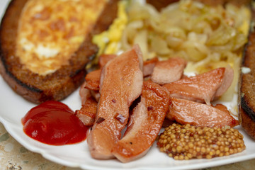 Simple and hearty dinner with fried eggs, onions and sausage on a white plate