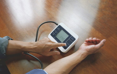 Man's hand resetting start button of digital blood presure monitor after very high systolic rate...