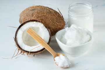 Coconut oil in a jar and coconut halves on the table on a white background