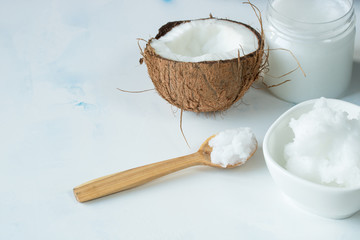 Coconut oil in a jar and coconut halves on the table on a white background