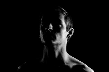 Dramatic portrait of a guy on a black background, black and white photography