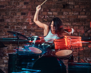 Fototapeta na wymiar Beautiful young girl musician playing on drums and cymbals. Live music in a night club