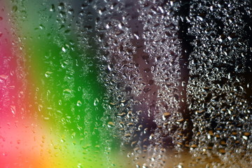 Abstract magical blurred colorfull rainbow aurora borealis on window glass with raindrops with multicolored lights with free copy space for text
