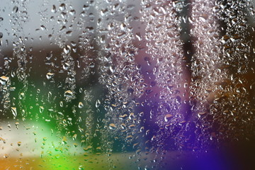 Abstract magical blurred colorfull rainbow aurora borealis on window glass with raindrops with multicolored lights with free copy space for text
