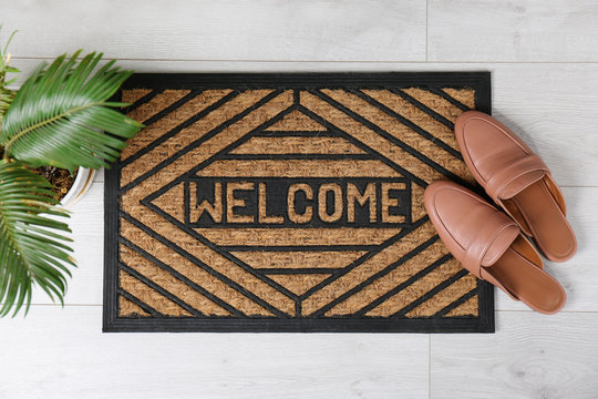 Door Mat With Word WELCOME And Shoes On Floor, Top View