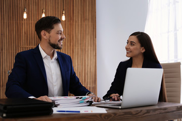 Office employees working with laptop and documents at table indoors