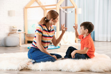 Hearing impaired mother and her child talking with help of sign language indoors