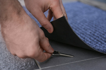 Man picking up key hidden under door mat, closeup view