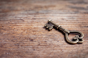 Old vintage key on wooden background, space for text
