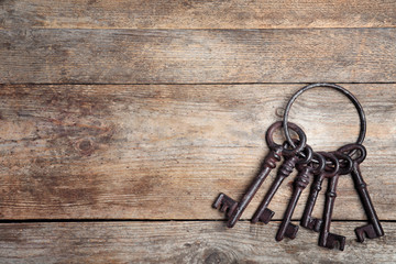 Bunch of old vintage keys on wooden background, top view with space for text