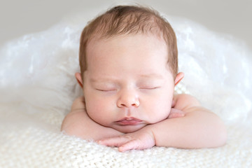 Isolated newborn / infant head resting on arms closeup