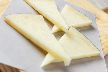 Manchego cheese on wooden board with olives