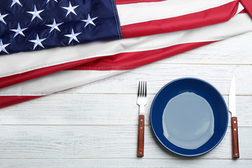 Patriotic table setting with USA flag on wooden background, flat lay. Space for text