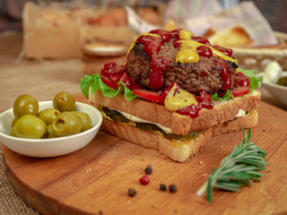 Toast with beef Patty, cucumbers, tomatoes and olives.