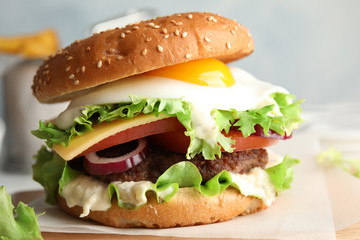 Tasty burger with fried egg on wooden board