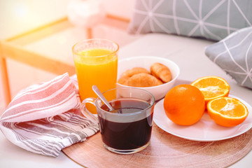 Croissants, black coffee, oranges and juice on the wooden tray. Breakfast in bed.