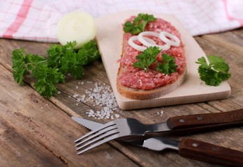 slice of bread with minced meat, parsley and onions - on rustic wooden table - breakfast bread - pork mett