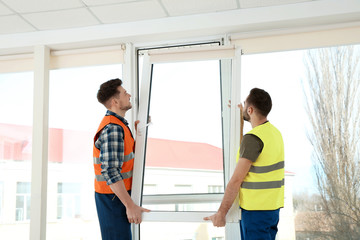 Construction workers installing plastic window in house