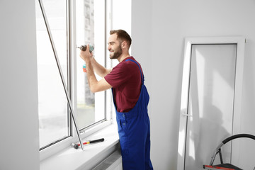Construction worker using drill while installing window indoors