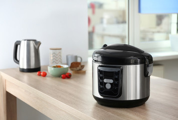Modern multi cooker and ingredients on table in kitchen