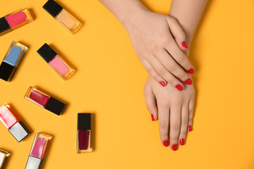 Obraz na płótnie Canvas Woman with red manicure and nail polish bottles on color background, top view