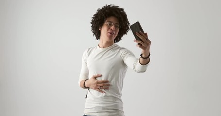 Young man with curly hair using mobile phone for video call