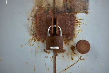 Brown lock on rusty grey iron door