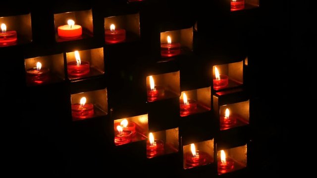 Burning beautiful red round prayer candles in a special niche in the darkness of a Catholic church