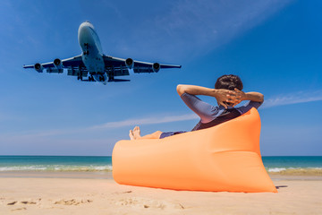 Man tourist have fun on the beach watching the landing planes. Traveling on an airplane concept. Text space. Island Phuket in Thailand. Impressive paradise. Hot beach Mai Khao. Amazing landscape